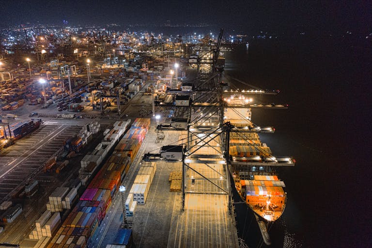 A captivating aerial view of Jakarta's bustling shipping port at night, showcasing vibrant activity.