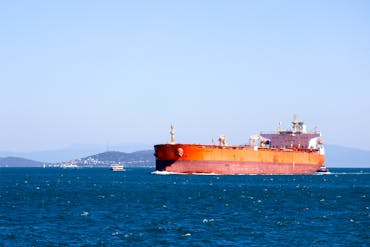 A large cargo ship navigating the open blue sea under a clear sky, showcasing maritime transport.